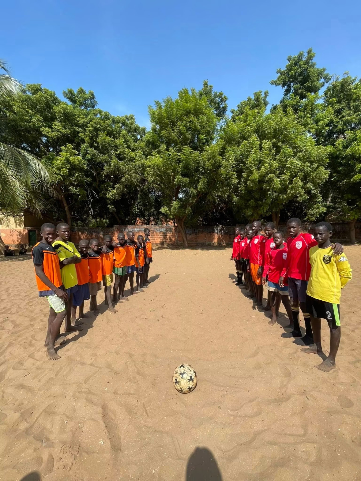 Deux équipes d'enfants alignées avant un match de football sur le sable