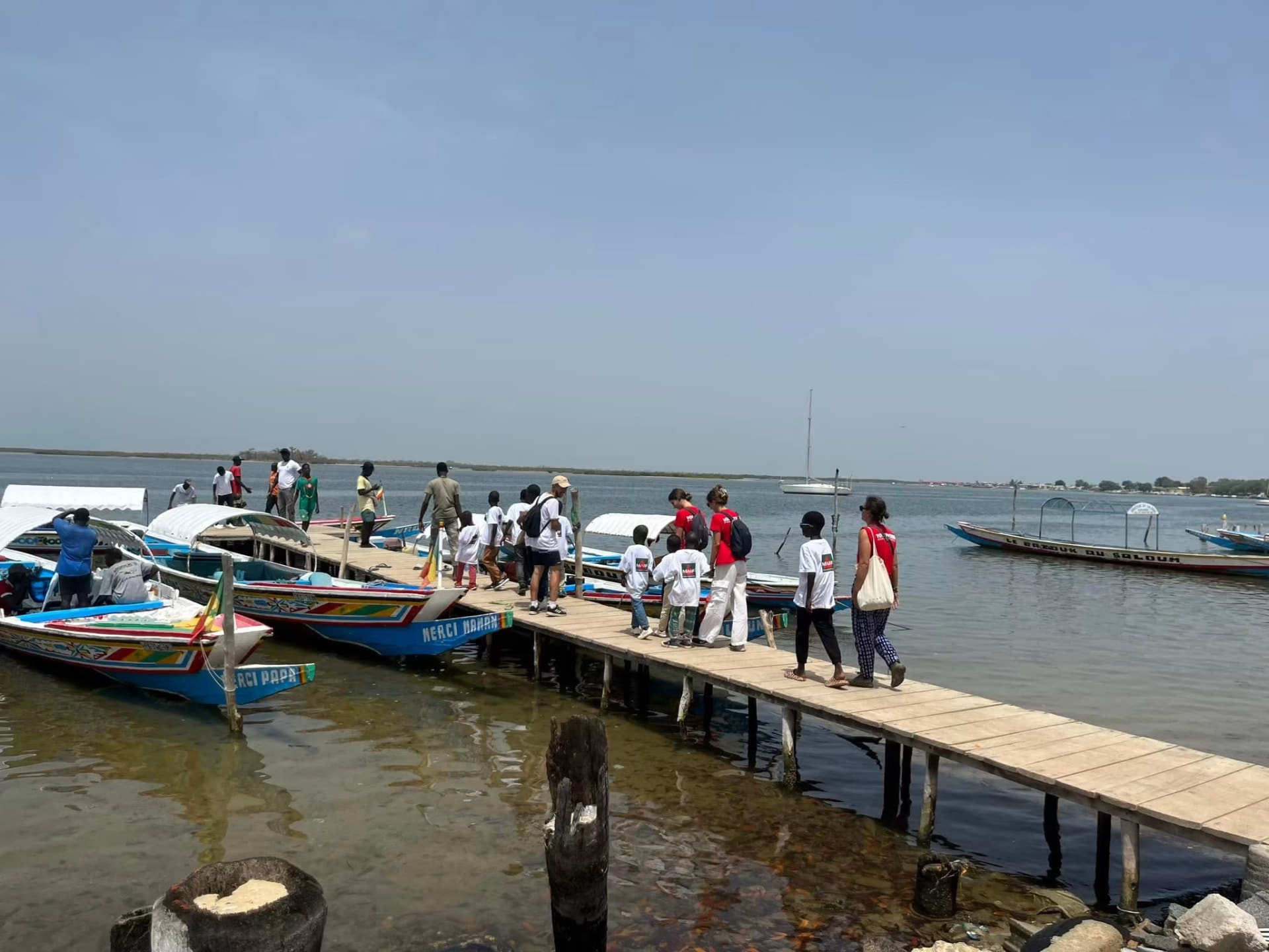 Enfants marchant sur un ponton entre des pirogues colorées