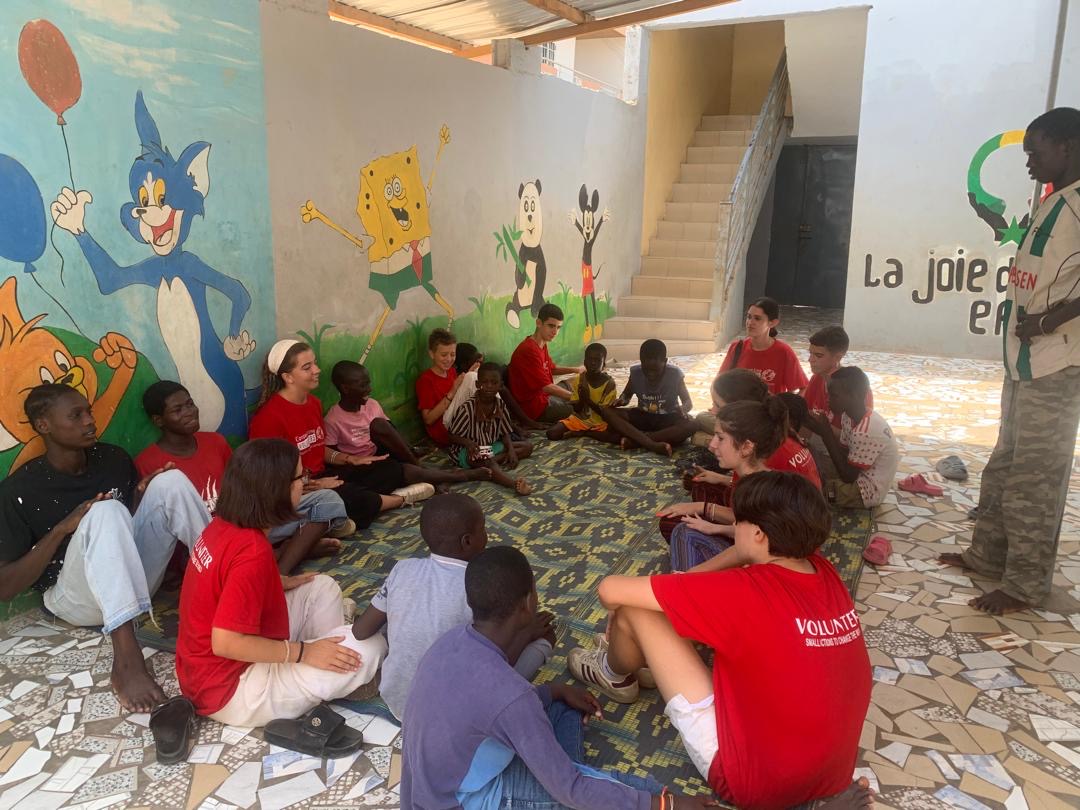 Cercle de parole entre bénévoles et enfants dans la cour du centre