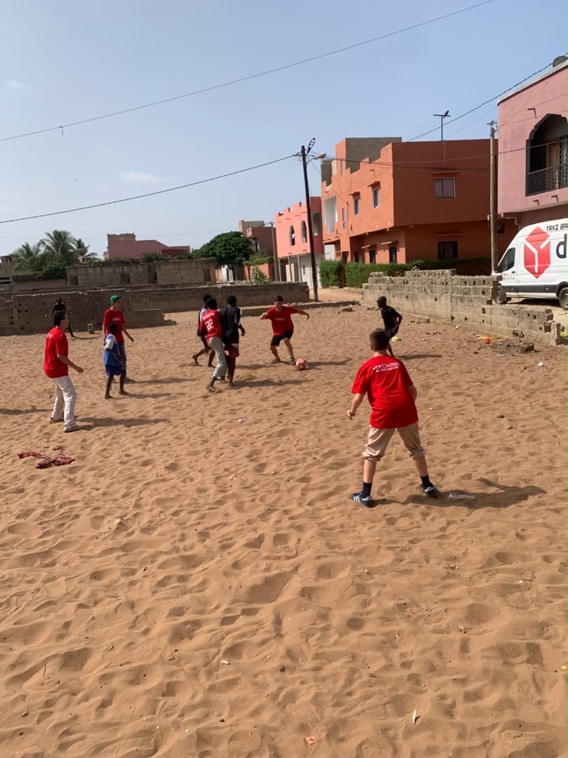 Bénévoles et enfants jouant au football sur le terrain de sable