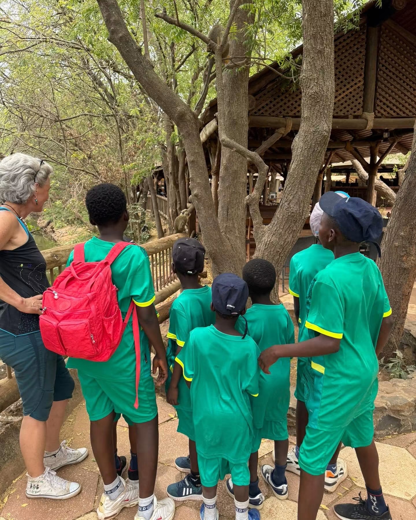 Enfants en tenue verte visitant la Réserve de Bandia avec une accompagnatrice