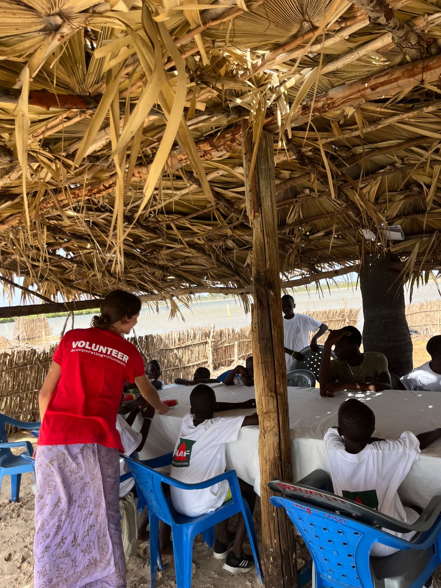 Bénévole servant des tranches de pastèque aux enfants sous une paillote