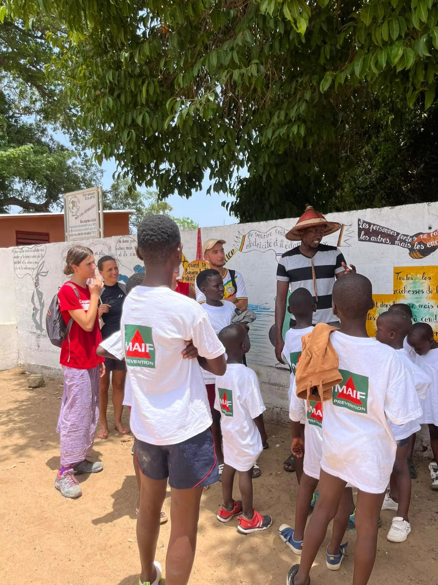 Enfants écoutant un animateur devant une fresque murale du centre