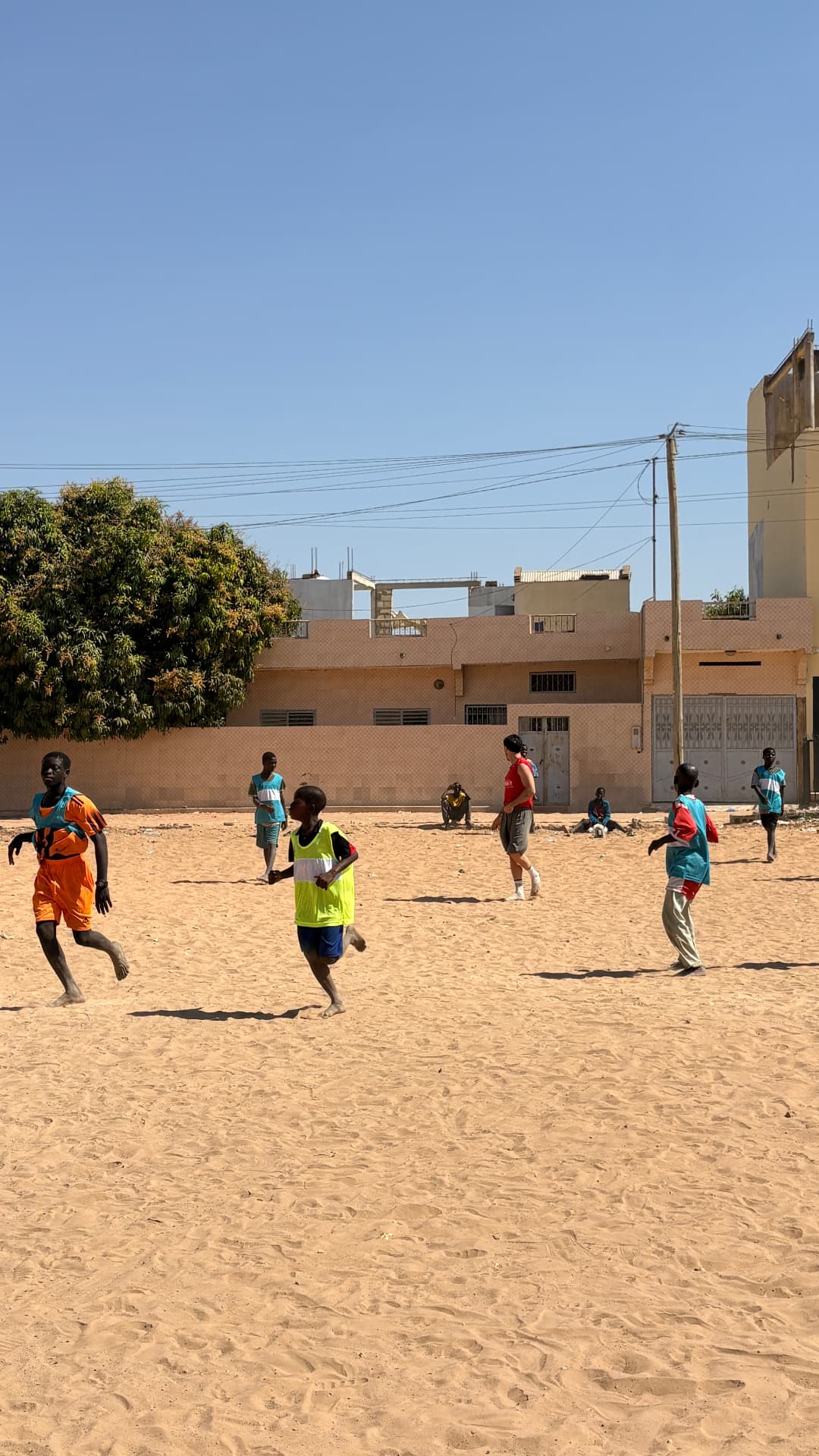 Enfants jouant au football sur un terrain de sable à Mbour