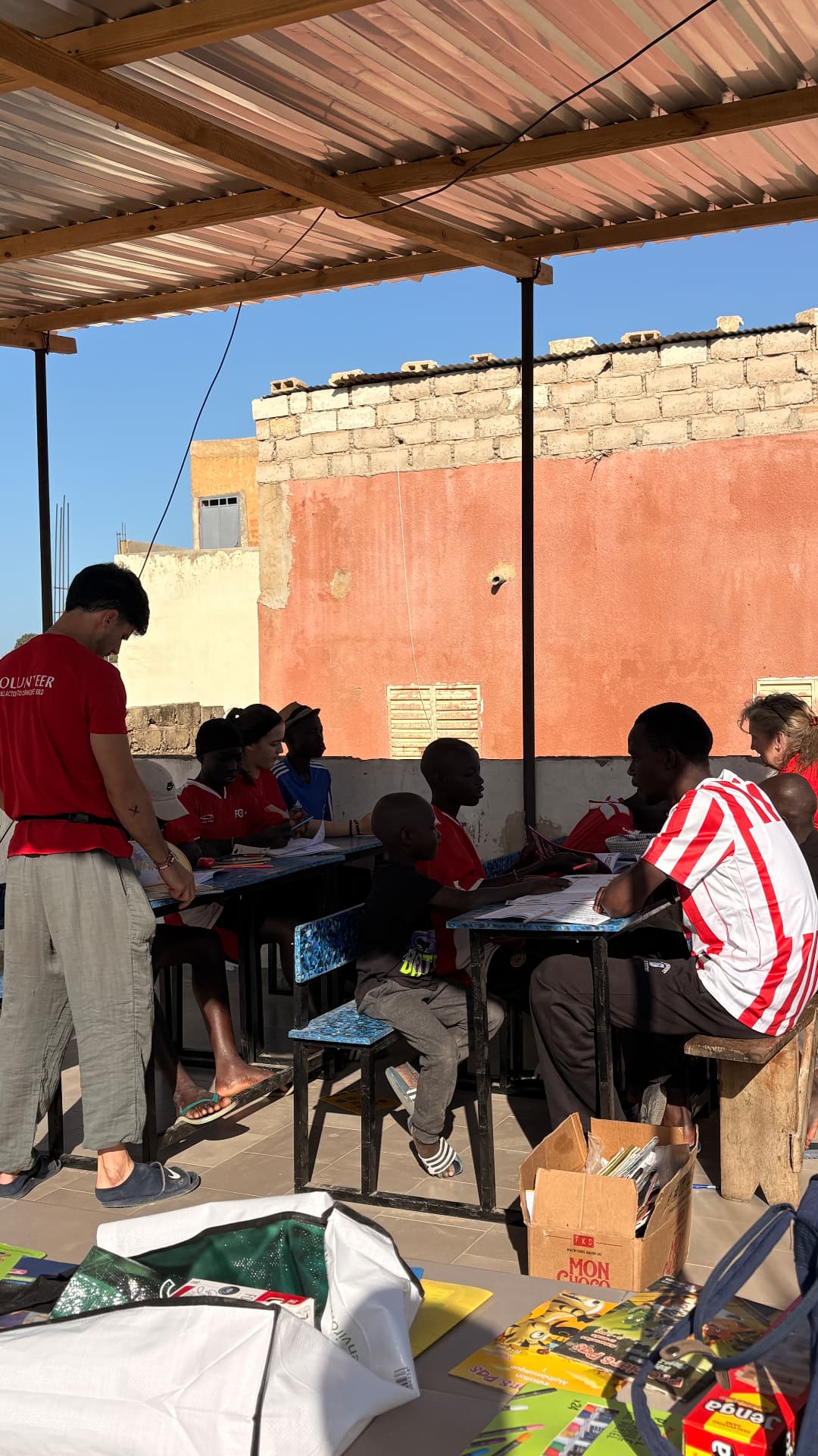 Enfants en cours avec des bénévoles sur la terrasse du centre