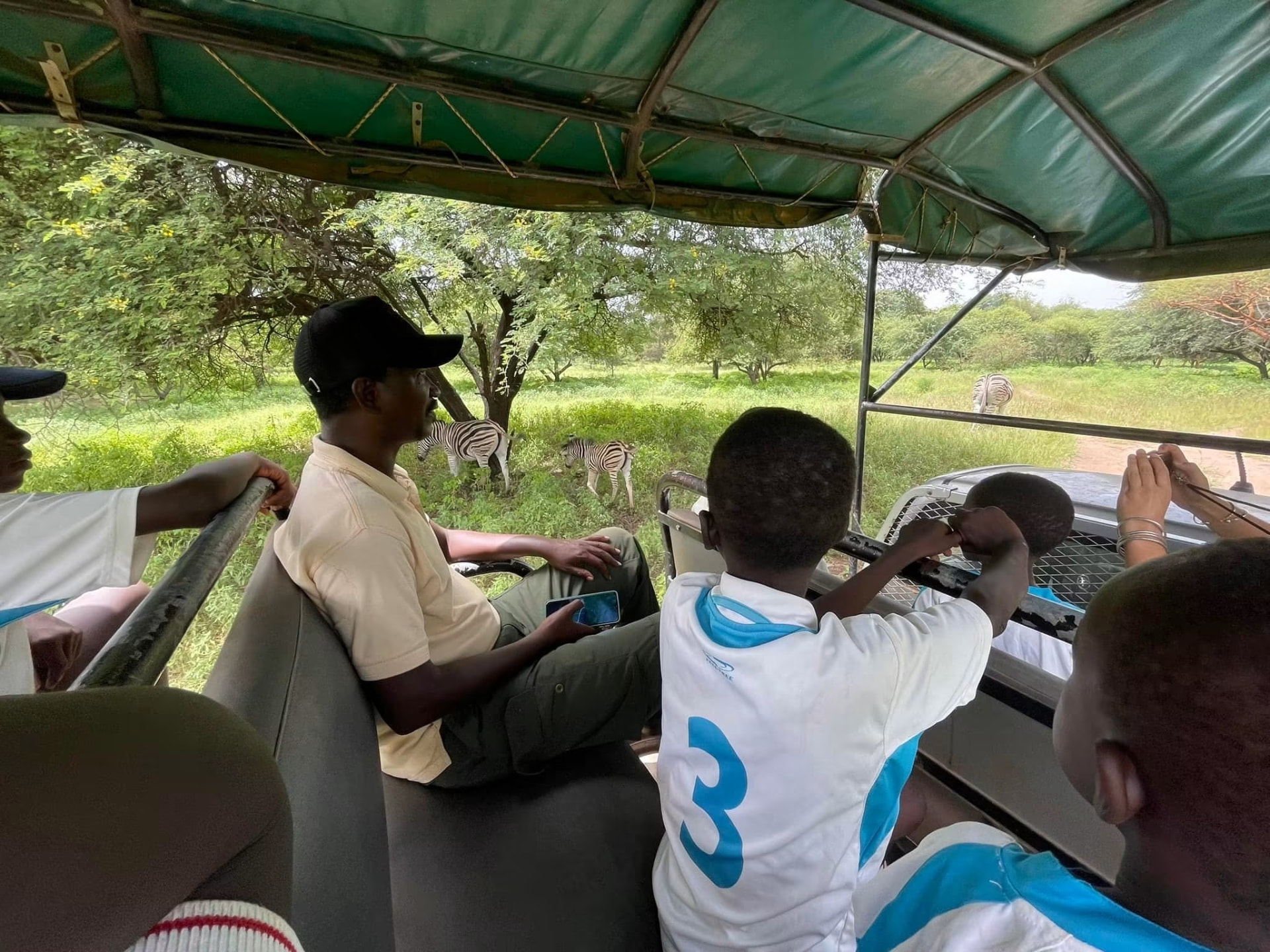 Enfants et guide observant des zèbres depuis un véhicule ouvert à la Réserve de Bandia